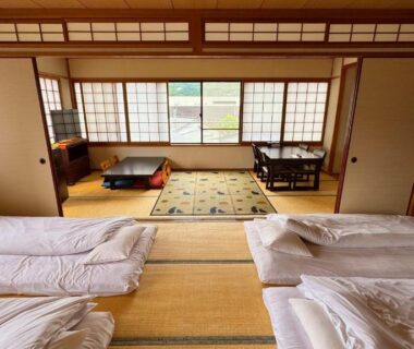 Tatami room with futon bedding, shoji screens and low table at Yufuin Akarinoyado in Ōita, Kyūshū