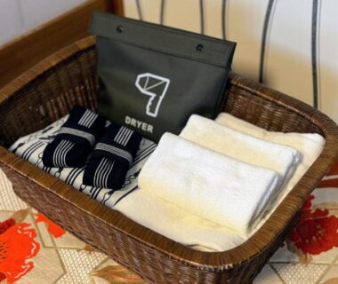 Woven basket with folded towels, striped yukata, and labeled dryer packet on patterned fabric