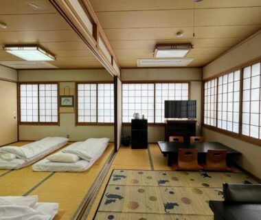 Spacious tatami room with folded futons, low table, shoji screens and seating at Yufuin Akarinoyado in Oita
