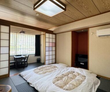 Japanese tatami room with futon bedding, shoji screens and low table at Yufuin Akarinoyado in Ōita, Kyūshū