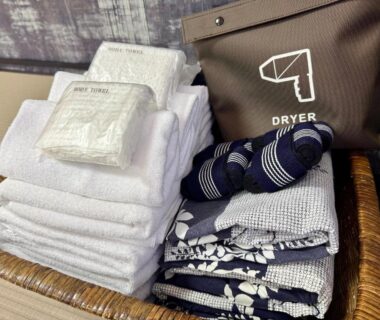 Folded towels, wrapped toiletries, yukata robes and slippers in a wicker basket at Yufuin Akarinoyado, Ōita