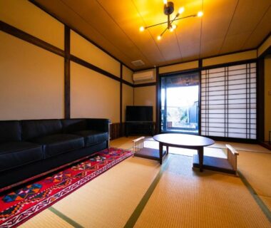 Tatami room with low table, shoji screens and dark sofa at Yufuin Bath Satoyamasafu in Oita