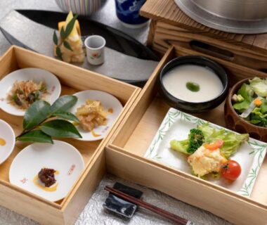 Wooden box meal with small dishes, a white bowl, salad and chopsticks at Yufuin Gettouan in Ōita