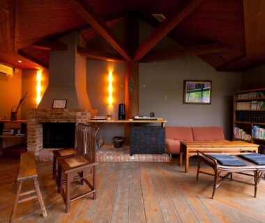 Warm lounge with fireplace, wooden beams and bookshelf at Yufuin Gettouan in Ōita, Kyūshū, Japan