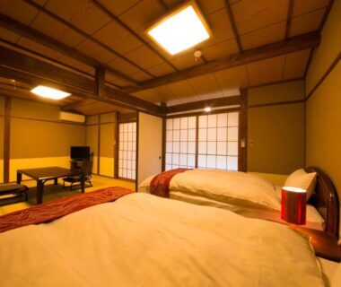 Two beds, shoji screens and low table in tatami room at Yufuin Gettouan, Ōita, Kyūshū