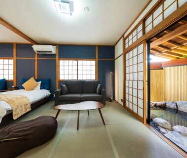 Tatami room with twin beds, sofa, low table and shoji doors opening to wooden bath in Yufuin, Ōita