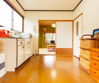 Kitchenette and wooden floor entry opening to a tatami room with shoji screens and dresser at Yufuin Inakamura Inakaso Ōita