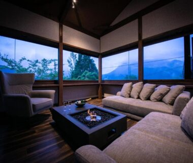 Cozy lounge with sofa and low table, large windows framing mountain view at Yufuin Kaze no Mori, Ōita