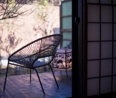 Metal lounge chair on wooden veranda framed by shoji screens at Yufuin Kaze no Mori, Ōita
