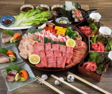Assorted sliced meats, vegetables and condiments arranged for tabletop grilling at a ryokan dining setting in Yufuin, Ōita