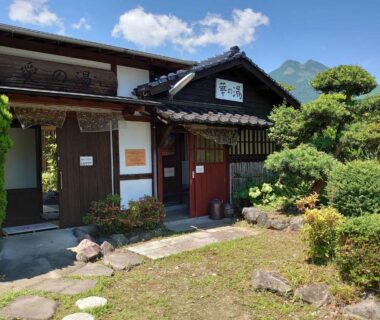 Wooden entrance with stone path and manicured garden at Yufuin Onsen Hasuwa Inn, Ōita