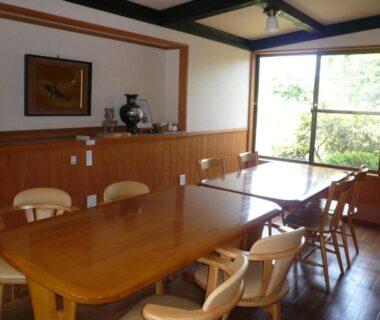 Long wooden communal dining table with chairs overlooking garden at Yufuin Onsen Hasuwa Inn, Ōita, Kyūshū