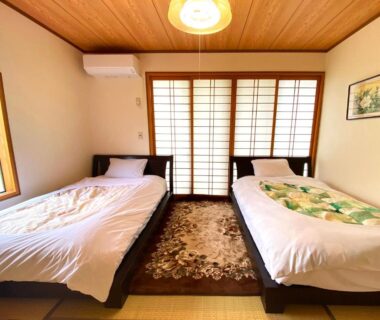 Tatami room with two beds and shoji screens at Yufuin Onsen Hasuwa Inn in Oita, Kyushu