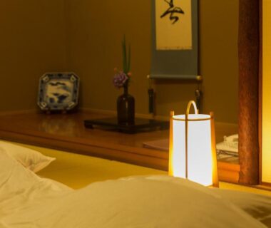 Tatami room with futon, tokonoma alcove with scroll and vase, soft lantern light at Yufuin Onsen Hinoharu Ryokan Ōita