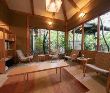 Wood-paneled lounge with tatami, low table and garden views at Yufuin Onsen Hinoharu Ryokan in Ōita, Kyūshū