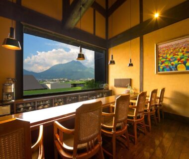 Counter seating facing large window with mountain view, warm wooden interior at Yufuin Onsen Toshoan, Ōita