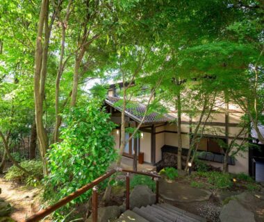 Stone steps leading through dense maple and evergreen trees to a traditional ryokan entrance at Yufuin Onsen Toshoan in Ōita