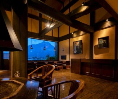 Interior lounge with exposed beams and low wooden seating at Yufuin Onsen Toshoan in Ōita, Kyūshū