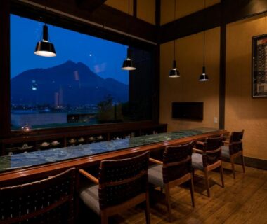 Long wooden counter with chairs and pendant lights at Yufuin Onsen Toshoan Ōita mountain view