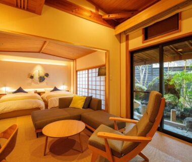 Tatami area with two beds, shoji screens and sliding doors to a garden at Yufuin Rakuyu, Ōita