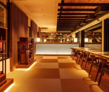 Ryokan lounge with wooden counter, stools and tatami flooring at Yufuin Rakuyu in Ōita, Kyūshū, Japan