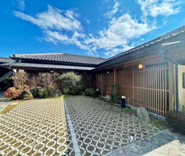 Sunlit courtyard with patterned paving and traditional wooden facade at Yufuin Ryokan Yamanami in Ōita, Kyūshū