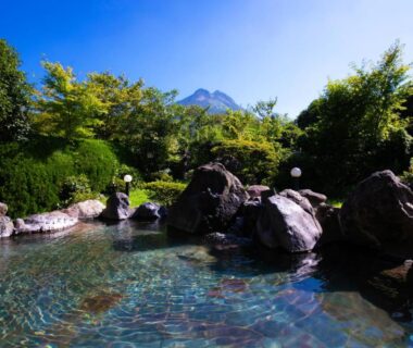 Rock lined outdoor onsen with clear water and mountain backdrop at Yufuin Sansuikan Oita, Kyushu