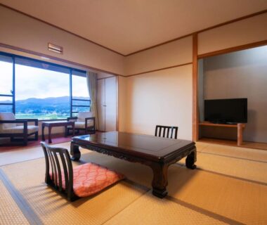 Traditional tatami room with low table and cushions, window seating overlooking Yufuin mountains in Ōita