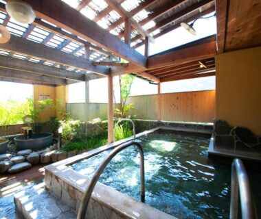 Wooden indoor onsen bath with skylight and garden view at Yufuin Sansuikan in Ōita, Kyushu