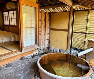 Wooden soaking tub on stone patio beside tatami room with shoji screens at Yufuin Santoukan, Ōita Japan