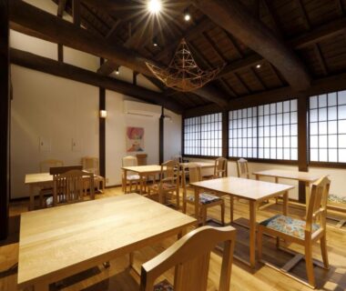 Interior dining area with wooden tables, shoji screens and exposed beams at Yufuin Souan Kosumosu, Oita