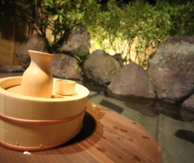 Wooden tub and cup on deck beside onsen bath and rock garden at Yufuin Tabinokura, Ōita, Kyūshū, Japan