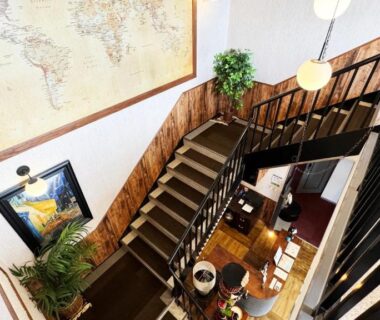 Interior view of wooden staircase and multi-level lobby with map artwork at Yufuin Tabinokura, Oita, Kyushu