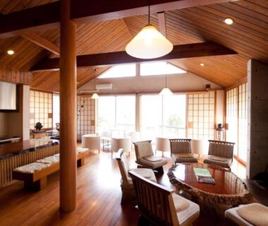 Spacious wooden lounge with vaulted ceiling, shoji screens, seating area and large windows at Yufuin Tsubaki, Ōita