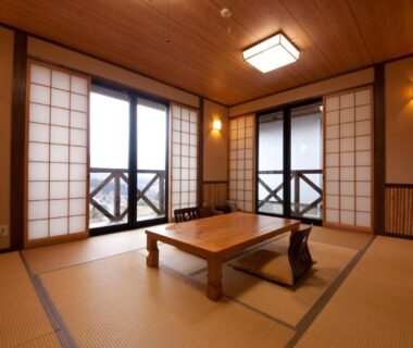 Tatami room with low wooden table, shoji screens and balcony railing at Yufuin Tsubaki, Ōita