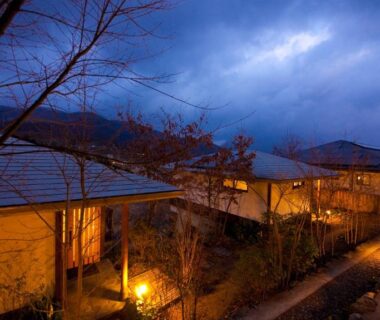 Twilight walkway and lit ryokan buildings at Yufuin Tsubaki in Ōita, Kyushu