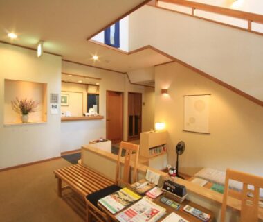 Interior reception lounge with wooden seating, brochures, staircase and check-in desk at Yufuin Yamaboushi, Ōita