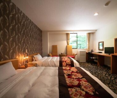 Spacious twin room with floral bed runners, desk and window overlooking greenery at Yufuin Yasuha in Kyūshū