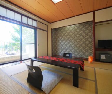 Japanese tatami room with low table, zabuton chairs, sliding doors and garden view at Yufuin Yasuha, Ōita