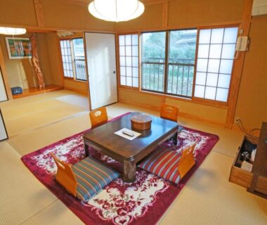 Traditional tatami room with low table, floor chairs, shoji screens and adjoining room at Yufunoyado Kifu