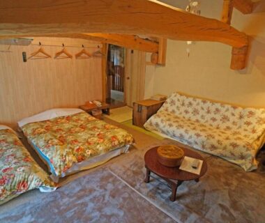 Cozy tatami room with futons, low table, sofa and exposed wooden beam at Yufunoyado Kifu, Ōita