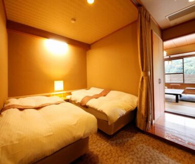 Western twin beds opening to tatami room with low table and floor cushions at Yugawara Ohnoya Ryokan, Kanagawa