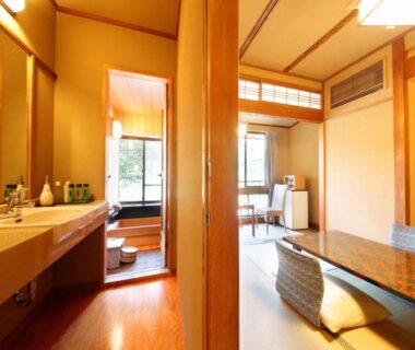Tatami room with low table, zabuton cushions and wooden bath area at Yugawara Ohnoya, Kanagawa