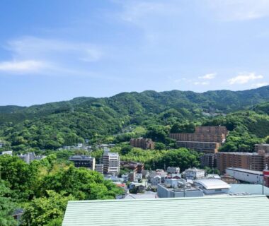 Rooftops and clustered buildings below verdant mountains surrounding Yugawara-Onsen in Kanagawa