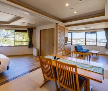 Spacious mixed tatami and Western-style room with beds, low dining table, seating area and large windows at Yugawara-Onsen Hotel Shiroyama
