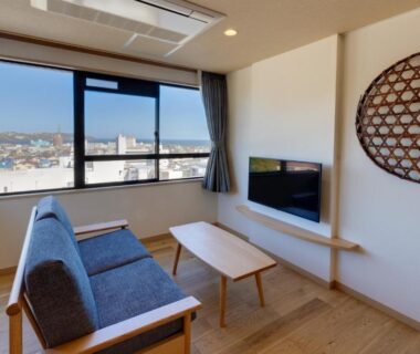 Sofa, low table and TV in wooden-floor sitting area with large window at Yugawara-Onsen Hotel Shiroyama Kanagawa Japan