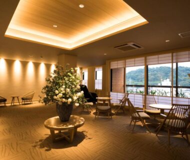 Spacious lounge with seating and floral centerpiece, windows overlooking outdoor greenery at Yugawara-Onsen Hotel Shiroyama, Kanagawa
