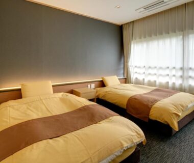 Two single beds with neutral duvets, carpeted floor, soft lighting and curtains at Yugawara Onsen Mizuno-kaori, Kanagawa