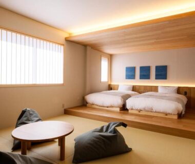Minimal tatami room with raised twin beds, low round table and floor cushions at YuhigauraOnsen Umi no Hana Kyoto