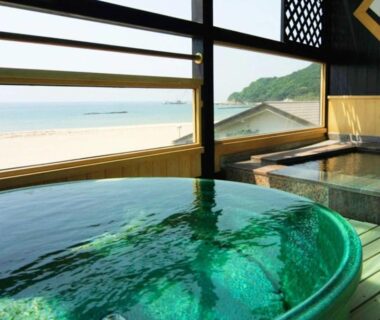 Round indoor soaking tub and wooden bathing area overlooking the beach and coastline at the Kyoto ryokan